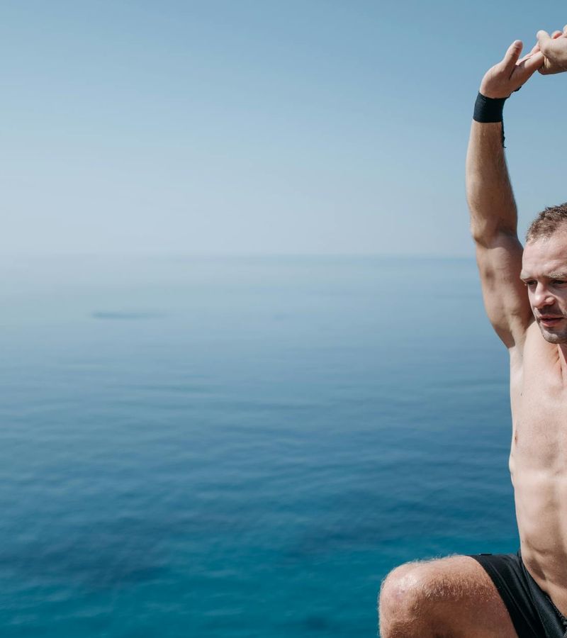 A man in a calm stretching pose outdoors with nature background.